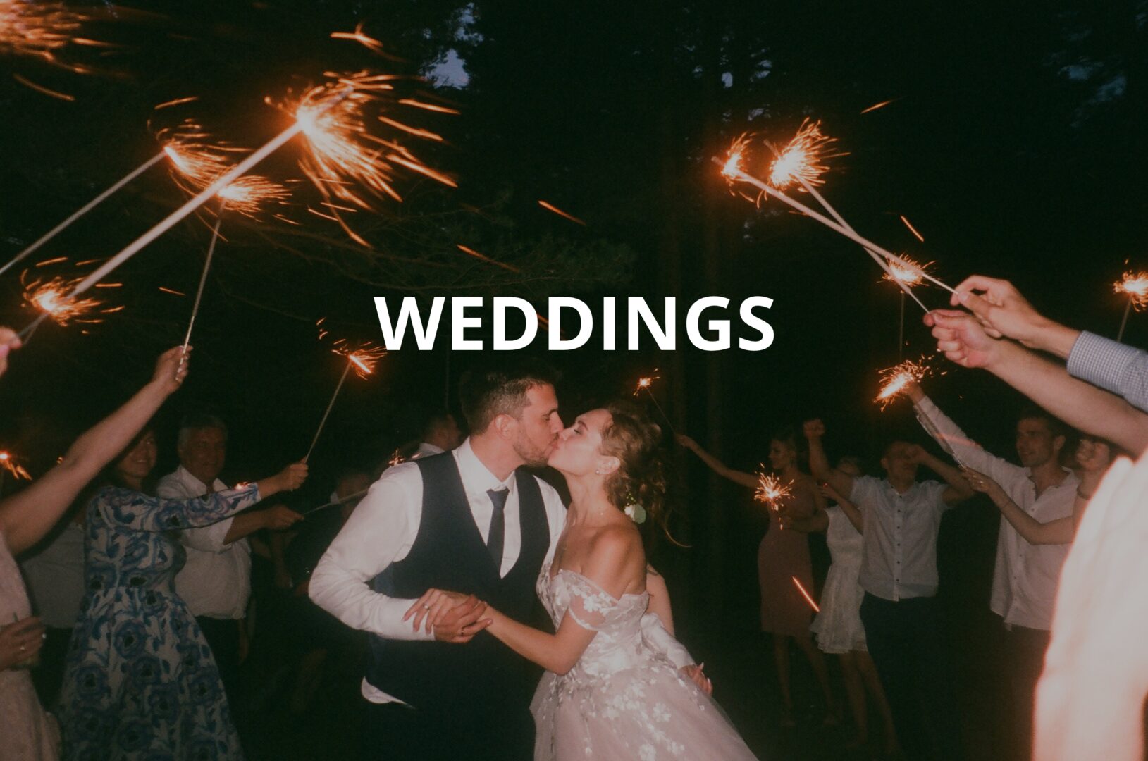 A couple is kissing in front of sparklers.